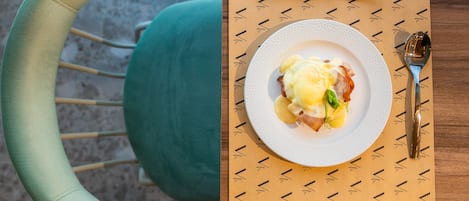 Une table à manger avec une assiette de nourriture, des couverts et un set de table à motifs.