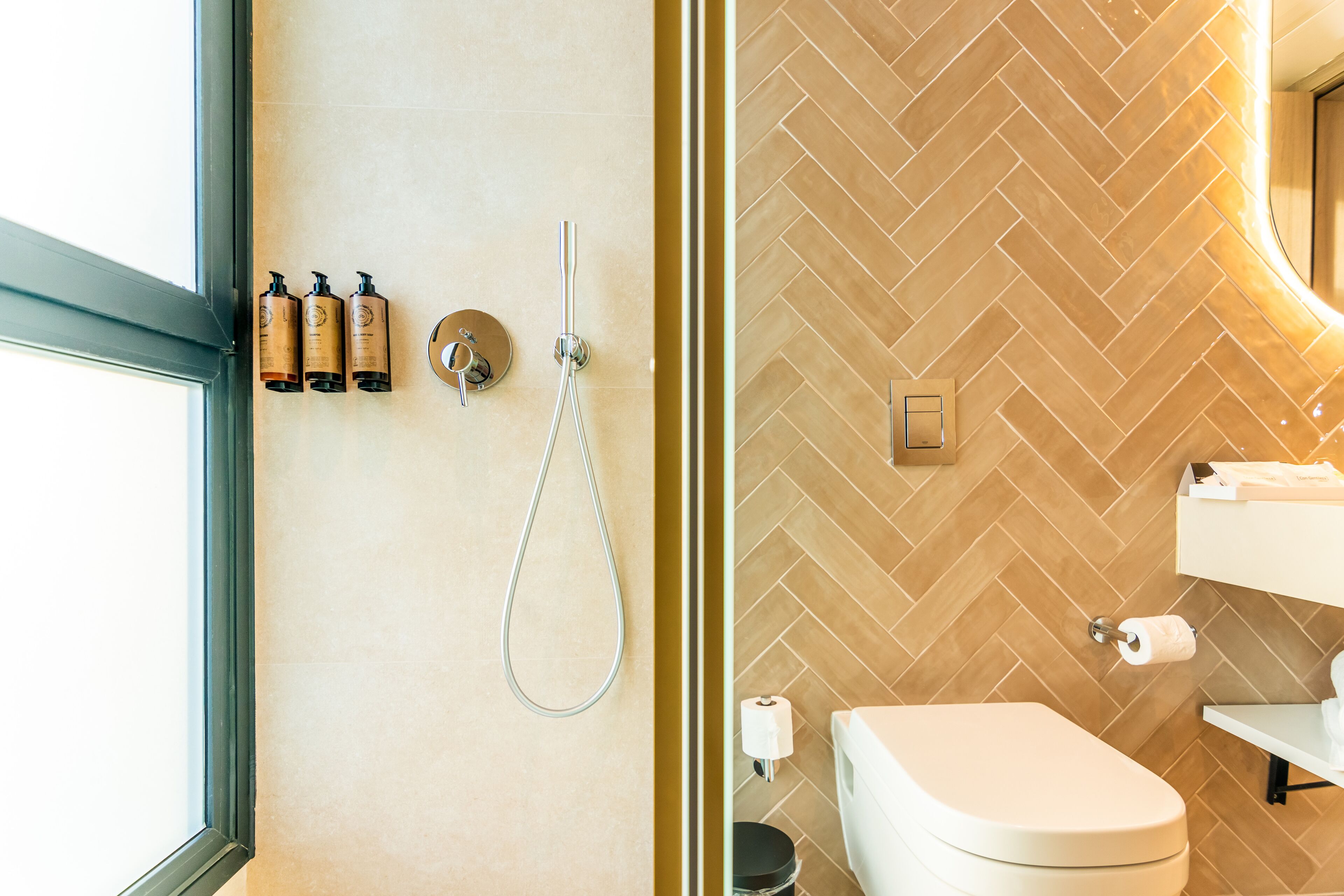 Baño con ziguezag de azulejos, inodoro, lavabo y ducha con puerta de cristal.