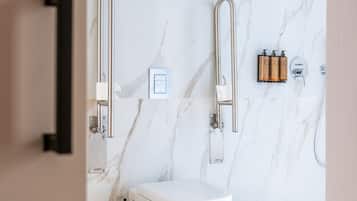 Un baño moderno con salpicadero de mármol, inodoro, bidé y cubo de basura.