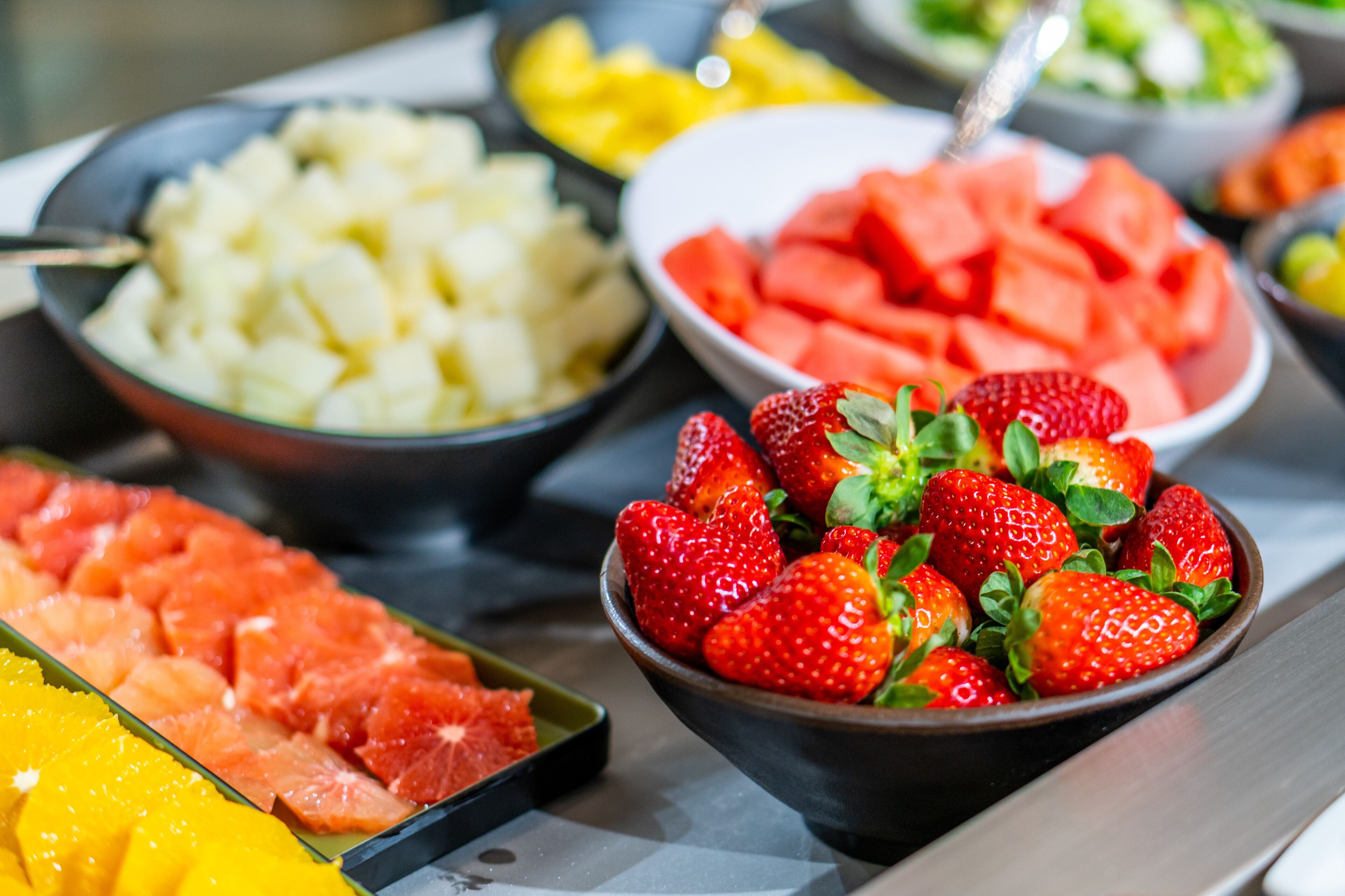 Un buffet proposant une variété de fruits, notamment des fraises, de la pastèque et de l’ananas.
