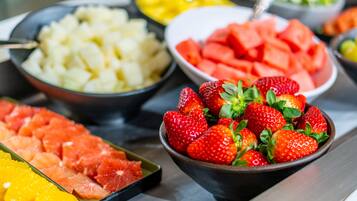 Un buffet proposant une variété de fruits, notamment des fraises, de la pastèque et de l’ananas.