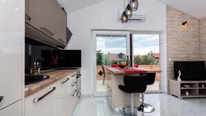 Una cocina moderna con una isla grande, una zona de comedor con taburetes de bar y un televisor en la sala de estar.