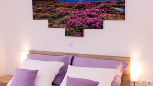 Un dormitorio con cama, almohadas y un cuadro colgado en la pared de un paisaje.