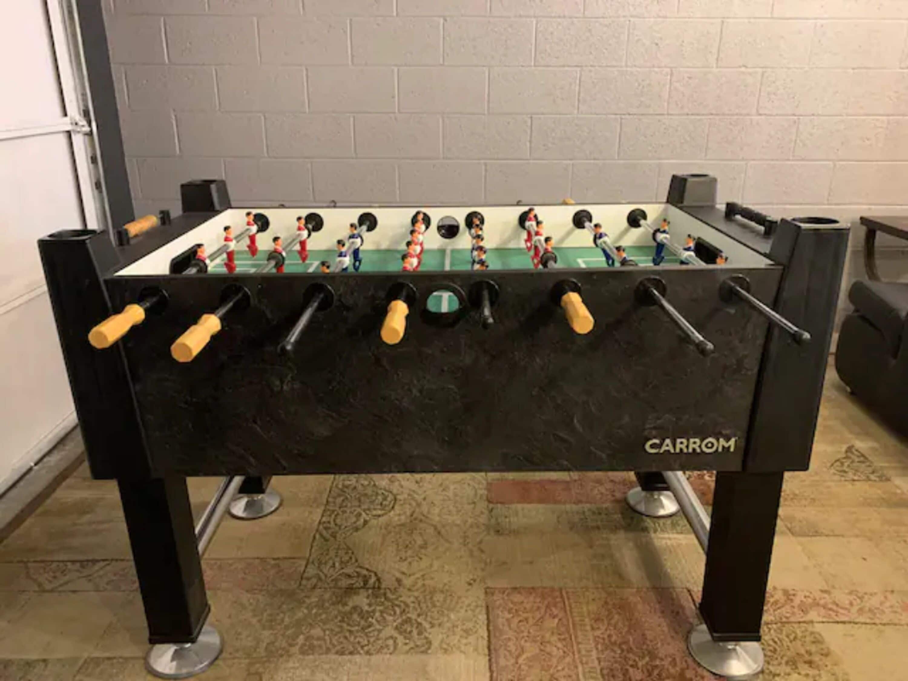 A foosball table with a black base and a Carrrom brand logo.