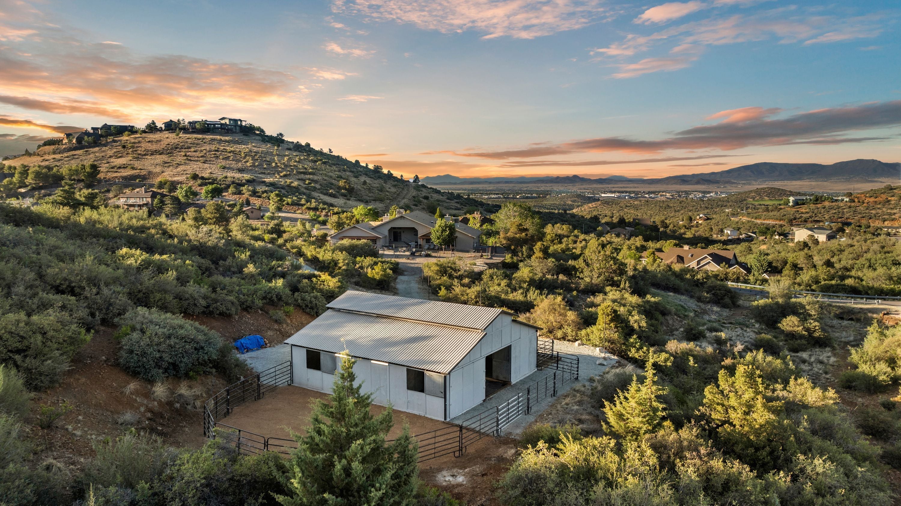 Uma região isolada e montanhosa com uma casa moderna pequena, um telhado de metal e uma entrada com calçada de cascalho.