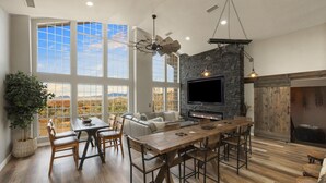 A spacious living area with a fireplace, large windows, and a stone accent wall. - New Luxury Prescott Lynx B B 4k ft2 Sleeps 22 (Prescott)
