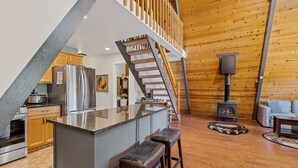 A kitchen with a stainless steel refrigerator, wooden cabinets, and a built-in island with bar stools. - Spacious A-frame Pines Cabin 12 Beds Loft Game Room (Flagstaff)