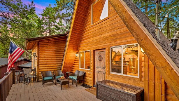 A wooden cabin with a deck, outdoor seating, and a flag. - Spacious A-frame Pines Cabin 12 Beds Loft Game Room (Flagstaff)