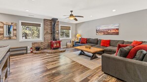 A living room with a fireplace, a sofa, a coffee table, and a painting on the wall. - Spacious Canyon Peak Pine View Home Game Room Hot Tub (Flagstaff)