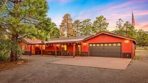 A red building with a garage, a covered porch, and a gravel driveway. - Spacious Canyon Peak Pine View Home Game Room Hot Tub (Flagstaff)