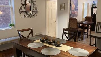 A dining area with a wooden table, four chairs, a bench, and a decorative mirror on the wall.