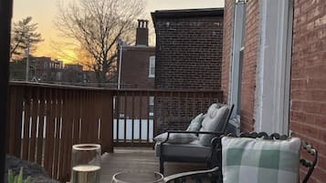 A patio with outdoor seating, a table with drinks, and a view of the sunset.