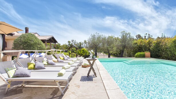 A poolside area with lounge chairs and a table, surrounded by greenery and a clear sky. - Your vacation surrounded by greenery at Villa Irde (6 rooms 6 bathrooms) (Alghero)