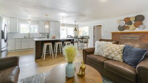 A spacious kitchen with white cabinets, a central island with stools, and a dining area in the background. - Chehalis Getaway w/ Golf Course View + Fire Pit! (Chehalis)