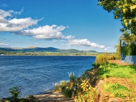 Un paisaje costero con vista despejada al mar, un camino que lleva a un acantilado y colinas distantes.
