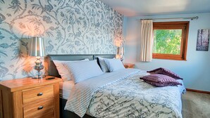 A bedroom with a bed, nightstands, a lamp, a window with curtains, and a patterned wallpaper. - Arenig - Bala Lake (Bala)