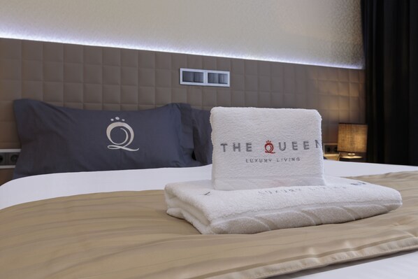 A neatly made bed with a folded white towel and a pillow with a logo.