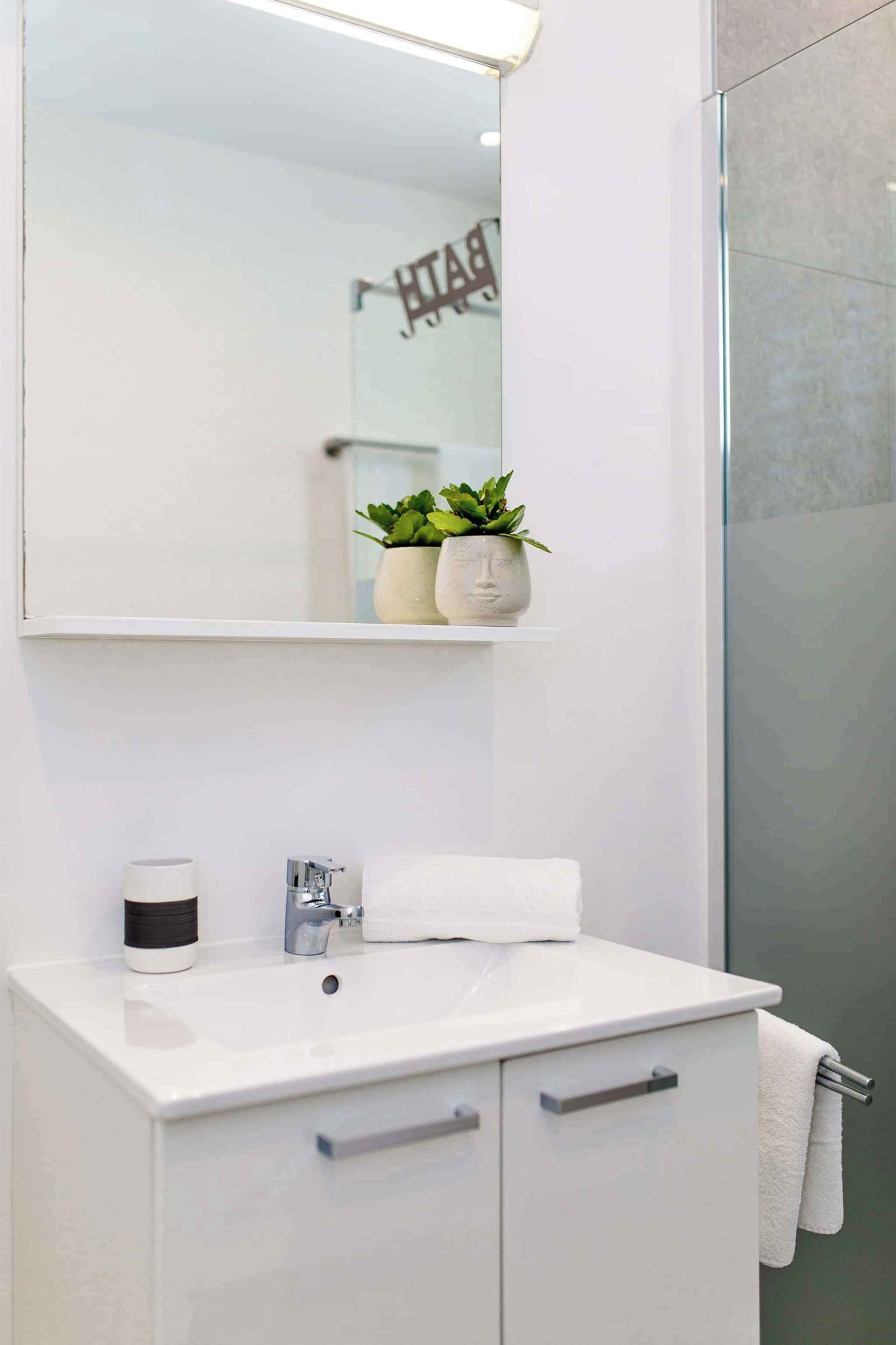 A modern bathroom with a white sink, a mirror, and a towel rack.