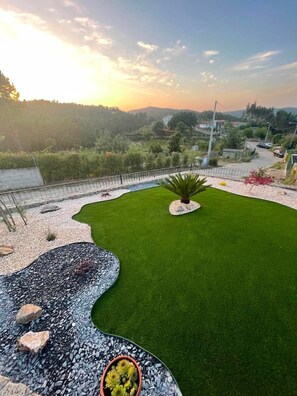 A landscaped garden with a well-maintained lawn, a rock feature, and a small tree.
