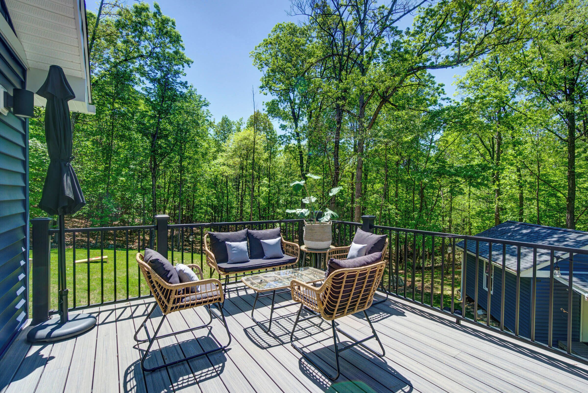 Une terrasse dotée de meubles en osier, d’une table et d’un petit abri de jardin.