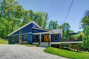 A two-story house with a porch, a deck, and a gravel driveway.