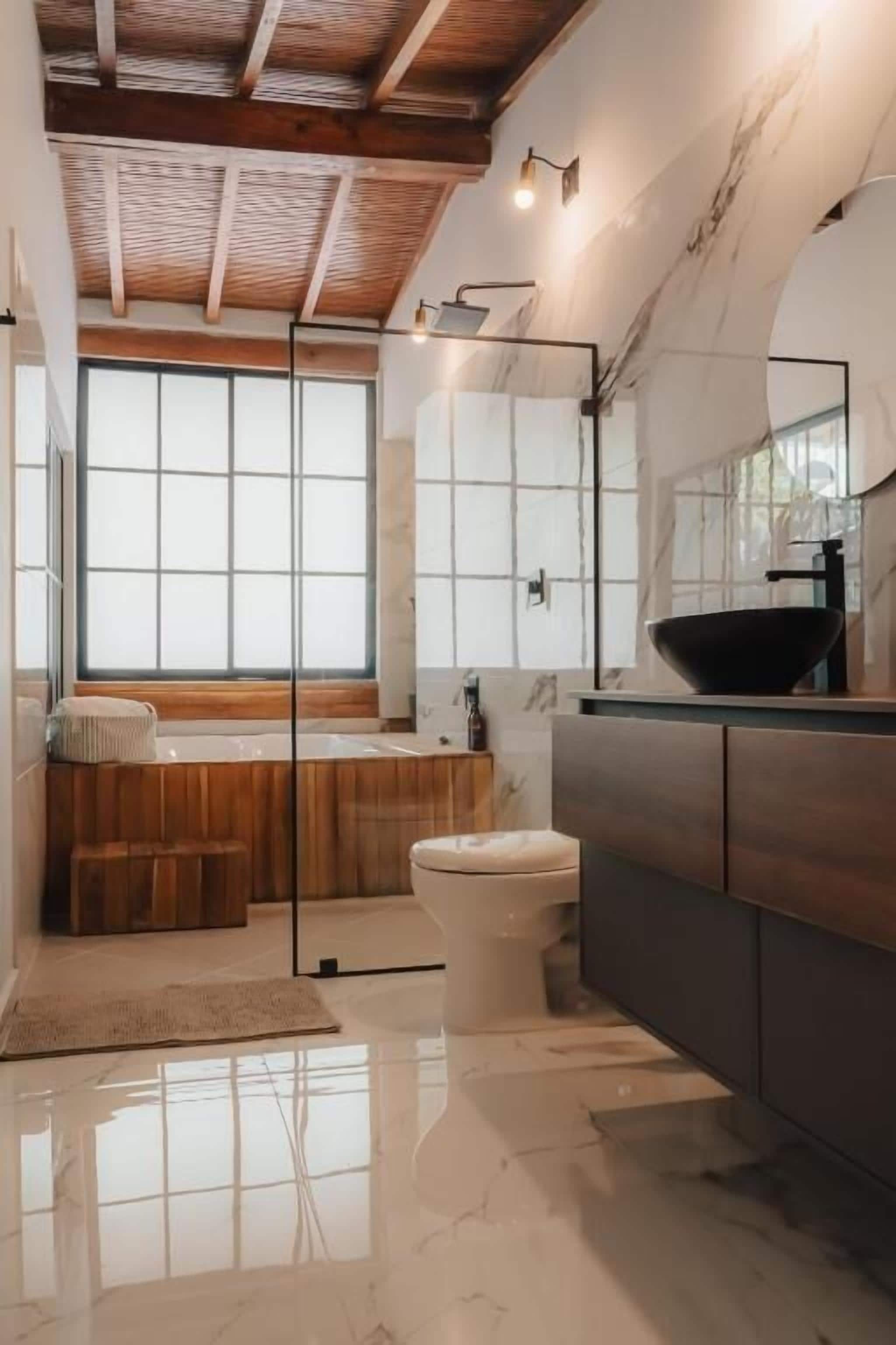 A modern bathroom with a bathtub, toilet, and vanity.