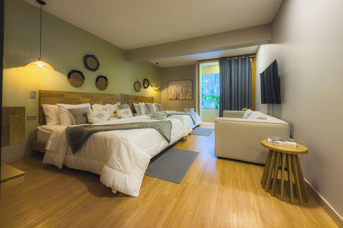 A spacious bedroom with a large bed, a sofa, and a television.