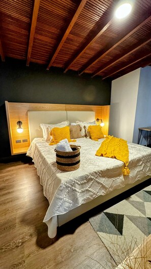 Une chambre avec un plafond en bois, un lit avec une literie blanche et jaune, et deux lampes de chevet.