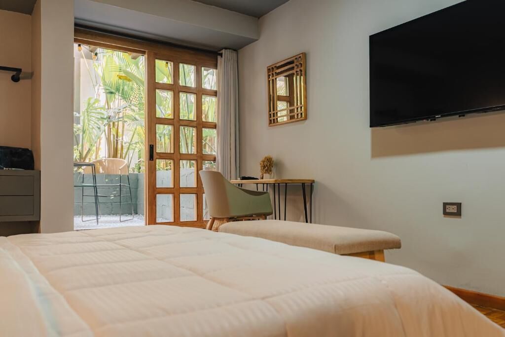 Ein Hotelzimmer mit einem Bett, einem Schreibtisch, einem Stuhl und einem an der Wand befestigten Fernseher.