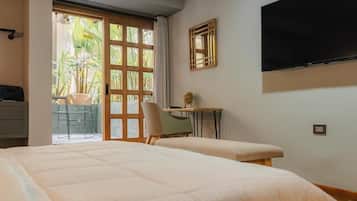 Una habitación de hotel con una cama, un escritorio, una silla y un televisor montado en la pared.