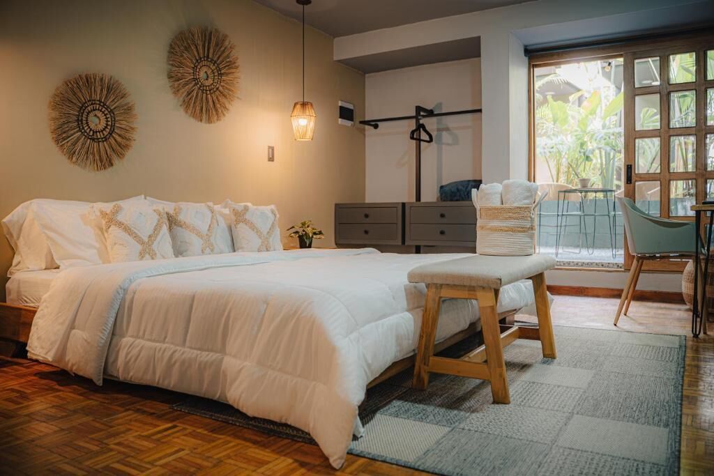 Un dormitorio con cama, mesita de noche, cómoda y vistas al exterior.