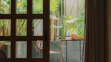 A room with a view of a garden through a window with multiple panes.