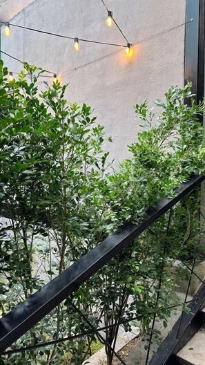 Un balcon avec une balustrade, des plantes et des guirlandes lumineuses.