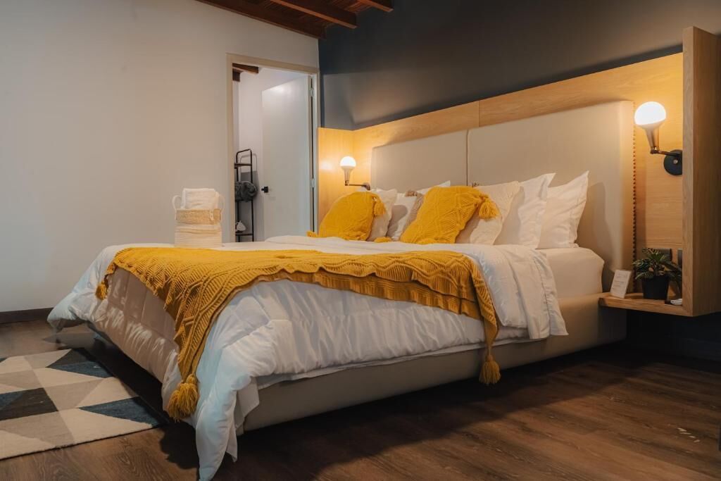 A modern bedroom with a bed, a bedside table with a lamp, and a door.