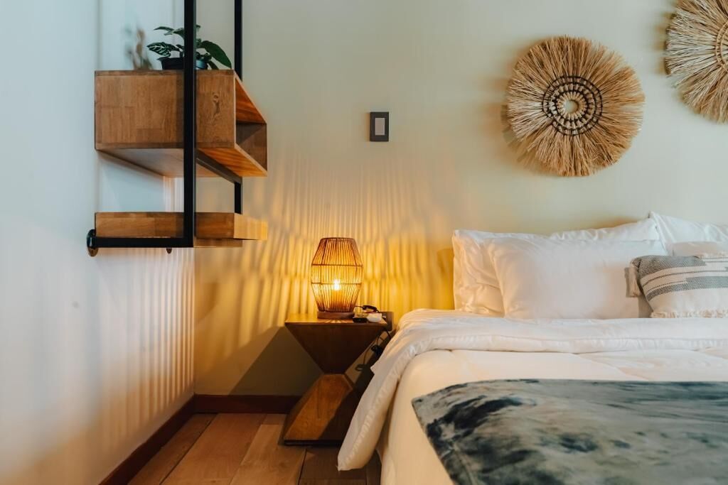 Un dormitorio con cama, mesita de noche, estanterías en la pared y decoración mural.