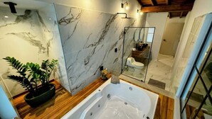 A modern bathroom with a marble wall, a wooden vanity, a bathtub, and a glass shower enclosure. - Muuk Boutique Hotel Campestre (Medellín)