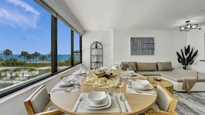 Ein Essbereich mit Blick auf das Meer, eine Couch und eine Pflanze.