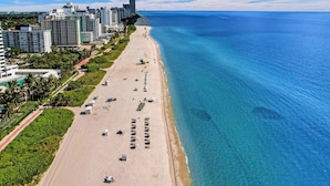 Eine Küstenstadt mit breitem Strand, Hochhäusern und klarem, blauem Wasser.
