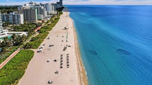 A coastal cityscape with a wide beach, high-rise buildings, and clear blue waters. - Fantastic condo w beach service/615 (Miami Beach)