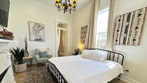 Un dormitorio con una cama grande, un candelabro, un cuadro y vistas al exterior.