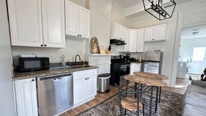 Una cocina moderna con armarios blancos, lavavajillas, microondas y un comedor con mesa y sillas redondas.
