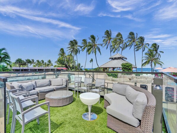 Relax in a serene outdoor lounge area with a variety of seating options and a stunning ocean view.