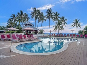 Relax by the pool surrounded by palm trees and enjoy the serene atmosphere.