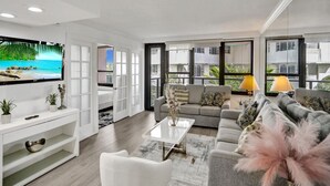 Ein modernes Wohnzimmer mit Flachbildfernseher, einer Couch, einem Couchtisch und einem TV-Schrank.