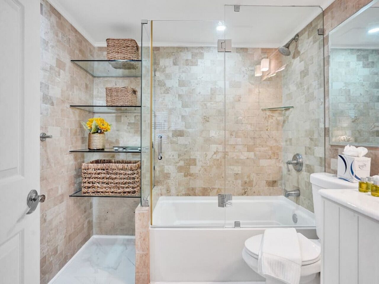 A modern bathroom with a glass shower enclosure, a freestanding bathtub, and a vanity with a mirror.
