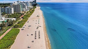 A coastal cityscape with a wide sandy beach, clear blue waters, and high-rise buildings. - Ocean View Condo / Beach Service & Pool / 618 (Miami Beach)