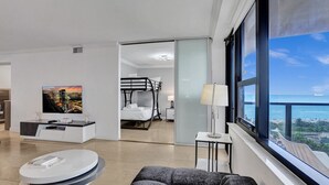 Una habitación de hotel moderna con balcón, televisor, literas y zona de comedor.