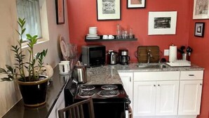 Une cuisine de taille réduite avec des meubles blancs, une cuisinière et une table à manger.