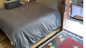 Une chambre à coucher avec un lit, des oreillers, un tapis, une porte et une fenêtre.