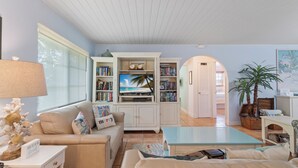A living room with a sofa, a coffee table, a TV, and a bookshelf. - CASA NEGRONI+DOCK+POOL 🔥❄️PETS+🔥Pit+TiKiBar+ Boat & Parking✅ (Marathon)